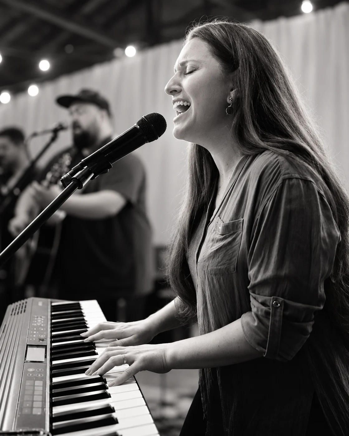 Cantora em ministração de adoração, cantando ao microfone e tocando teclado